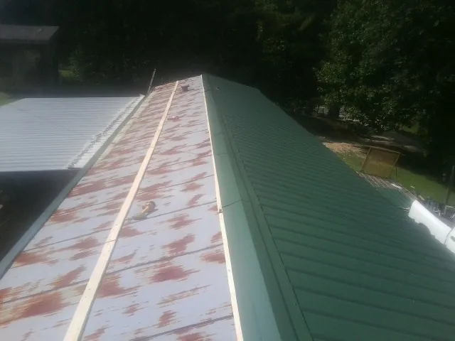Old rusted panels beside newly installed green metal roofing — Wind Damage Roof Repair by Roofing Brothers in Crested Butte