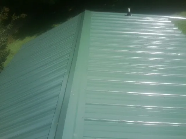 New green metal panels meeting at the ridge of a roof — Flat Roof Repair work by our crew in Crested Butte
