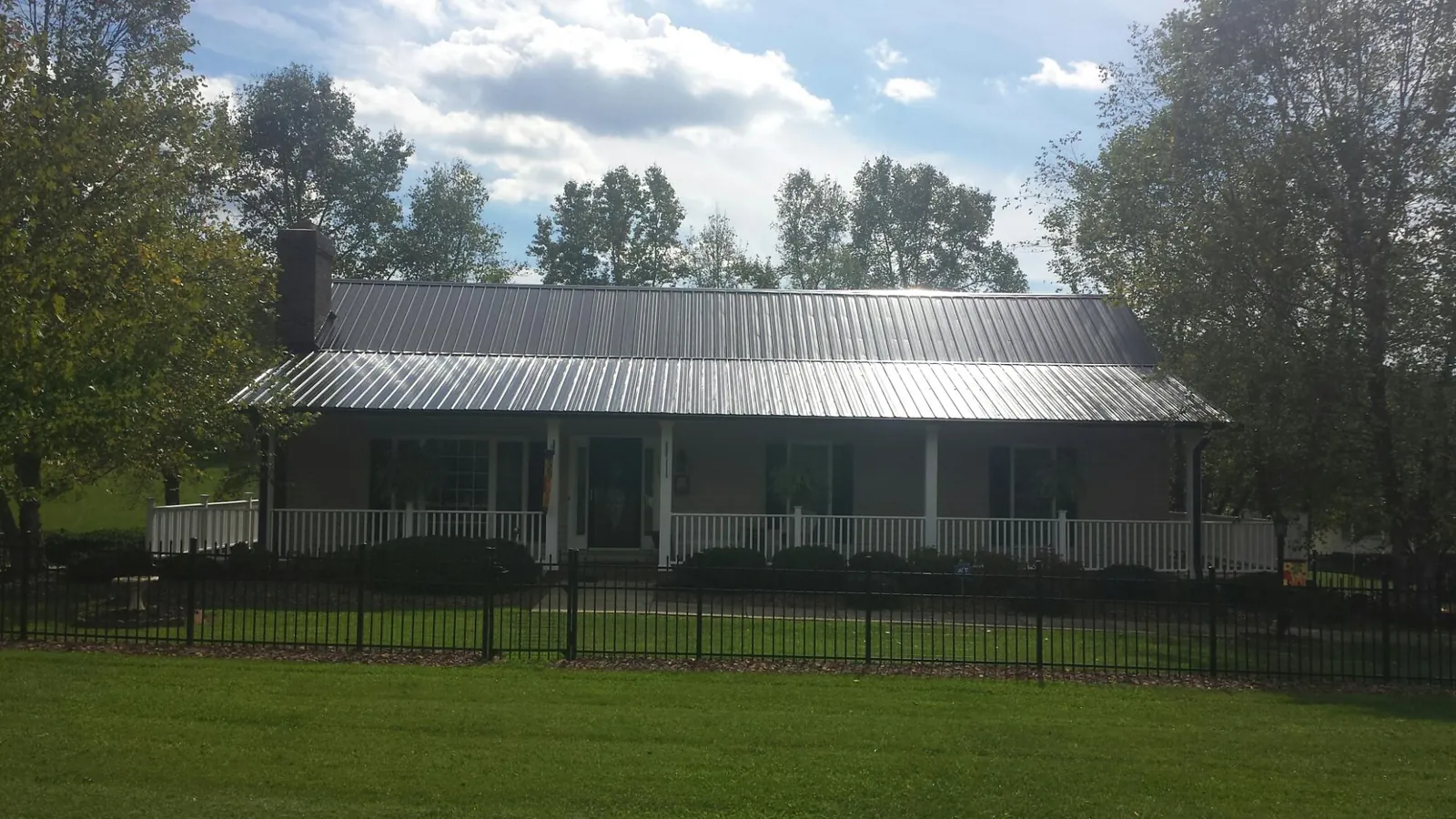 Gray metal roof on a brick ranch with a full width front porch — Gutter Guard Installation work by our crew in Crested Butte