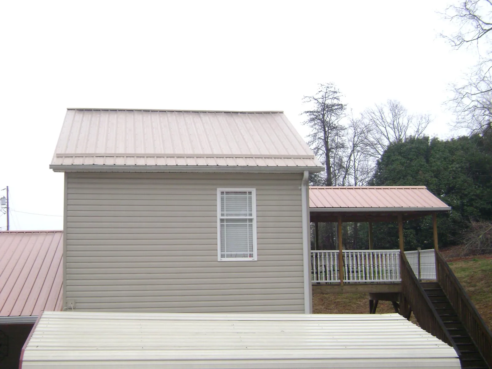 Tan metal roofs on a two story addition and attached porch, from a Roof Replacement job in Crested Butte