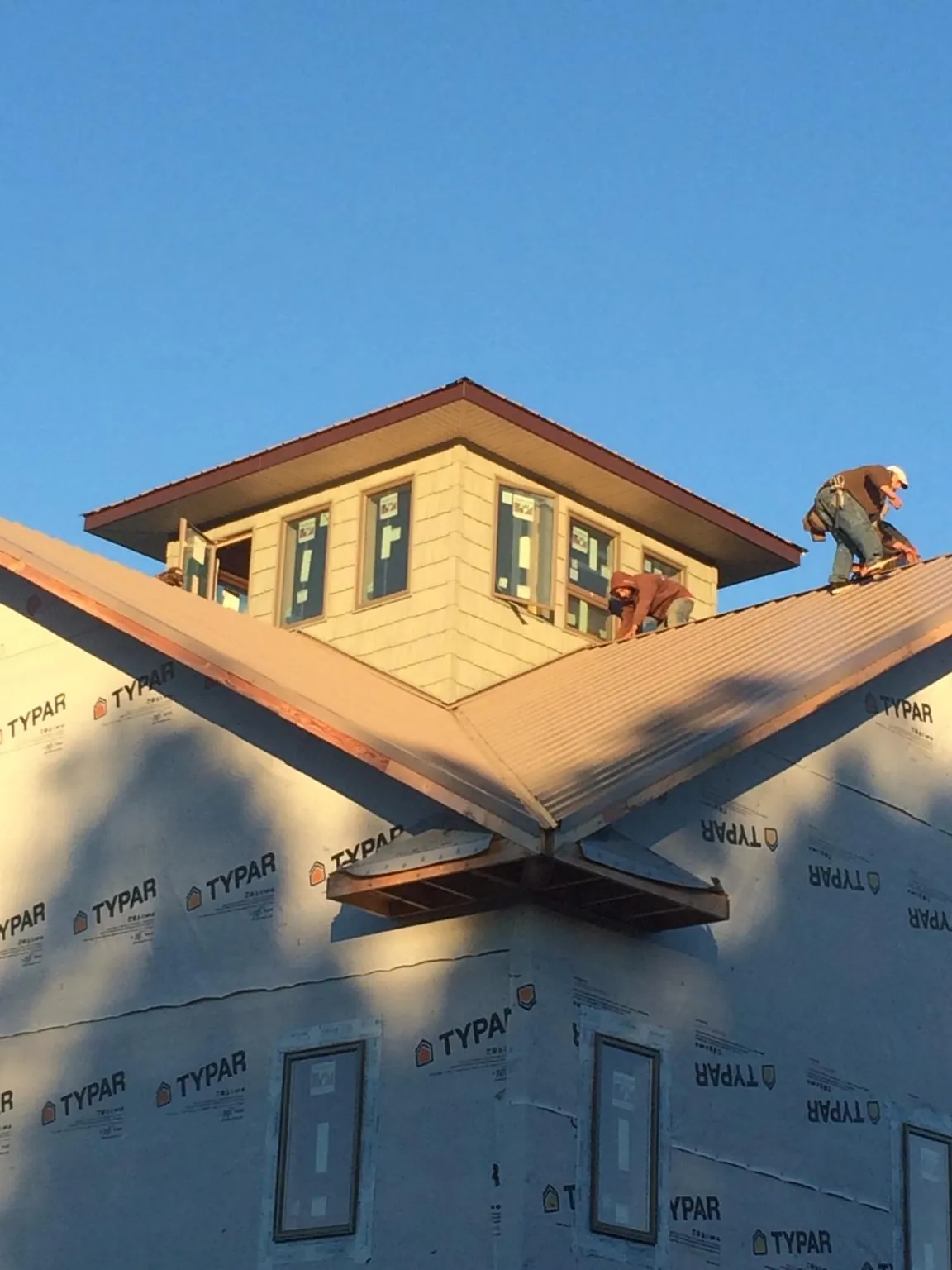 Roofers working around a rooftop cupola on a new metal roof at sunset — Roof Waterproofing in Crested Butte by Roofing Brothers